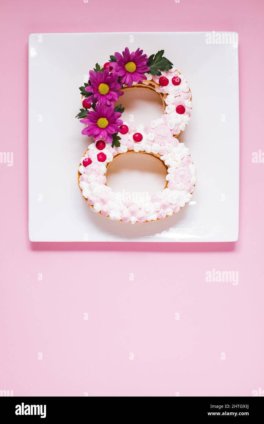 Gâteau de jour pour femmes en forme de huit sur fond rose. Concept du 8 mars. Journée internationale de la femme Banque D'Images