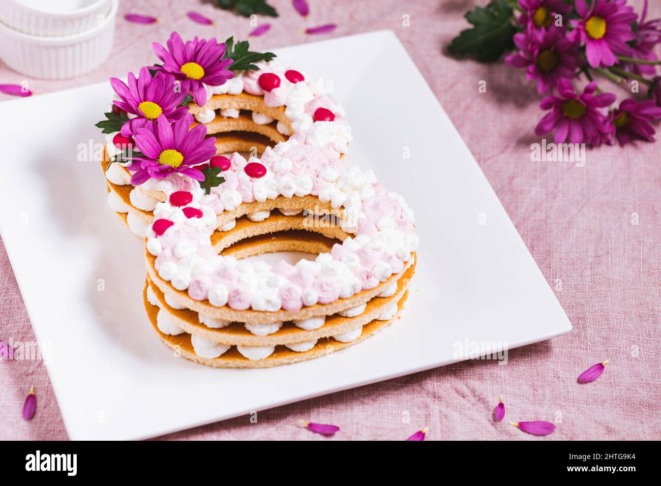Gâteau de jour pour femmes en forme de huit sur fond rose. Concept du 8 mars. Journée internationale de la femme Banque D'Images