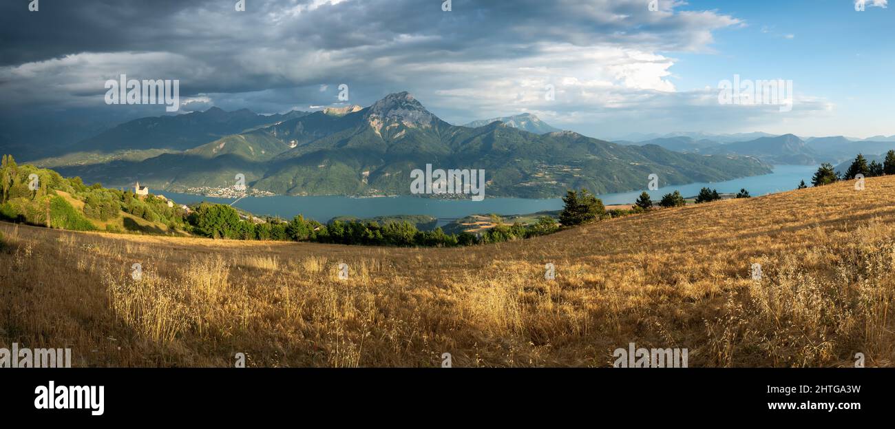 Lac de serre-Poncon en été avec une tempête imminente. Vue panoramique sur les villages de Saint-Apollinaire et de Savines-le-Lac. Hautes-Alpes (Alpes), France Banque D'Images