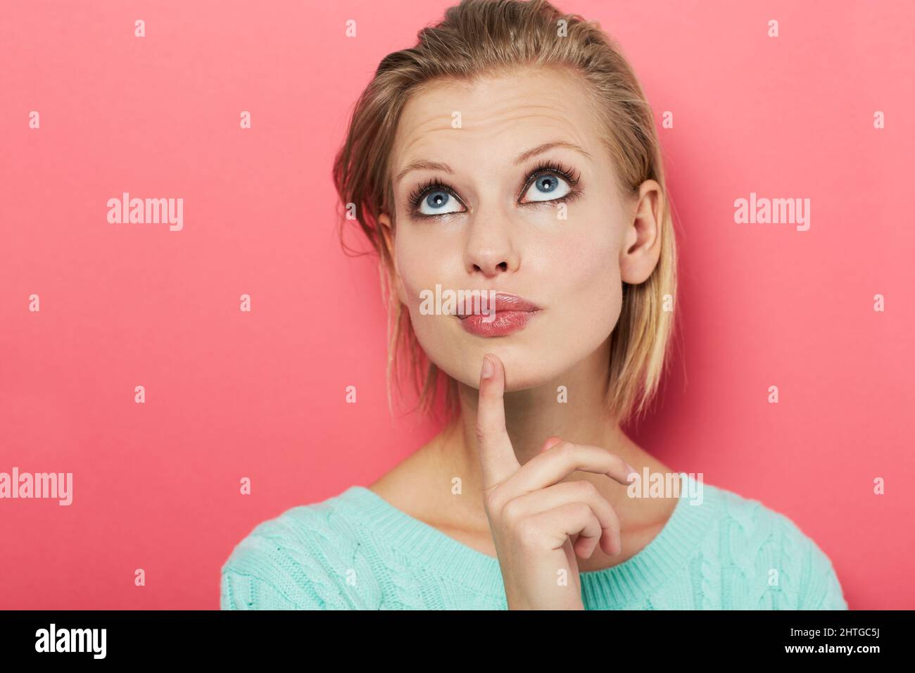 Choix difficile. Une belle jeune femme se pensant à elle-même alors isolée sur rose. Banque D'Images