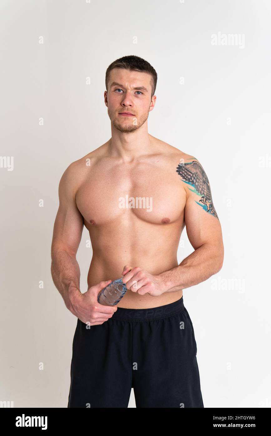 La forme physique à l'eau potable est pompée avec une serviette sur un fond blanc athlète de forme physique isolé boire adulte mâle tenue, pause serviette copier rythme Banque D'Images
