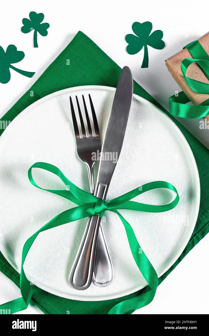 Assiette et couverts sur serviette verte. Table festive pour la Saint-Patrick. Shamrock symbole de chance. Banque D'Images