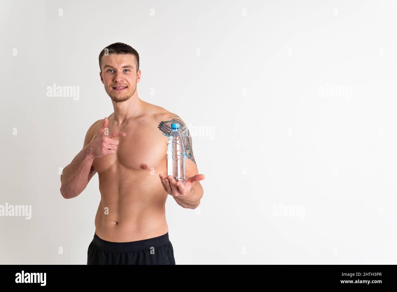 La forme physique masculine de l'eau potable est pompée avec une serviette sur un fond blanc isolé corps d'athlète fort, l'entraînement athlétique. Allure de puissance de culturisme Banque D'Images