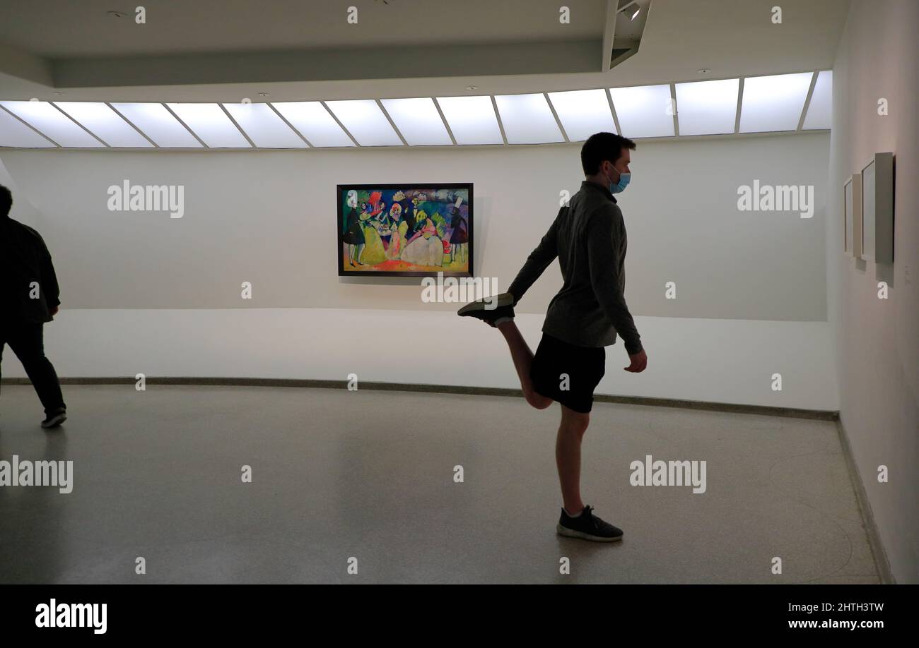 Un visiteur s'étirant la jambe dans la galerie du musée Guggenheim avec le groupe de Vasily Kandinsky dans les crinolines 1909 sur le mur d'arrière-plan.New York.New York.USA Banque D'Images Un visiteur s'étirant la jambe dans la galerie du musée Guggenheim avec le groupe de Vasily Kandinsky dans les crinolines 1909 sur le mur d'arrière-plan.New York.New York.USA Banque D'Images
