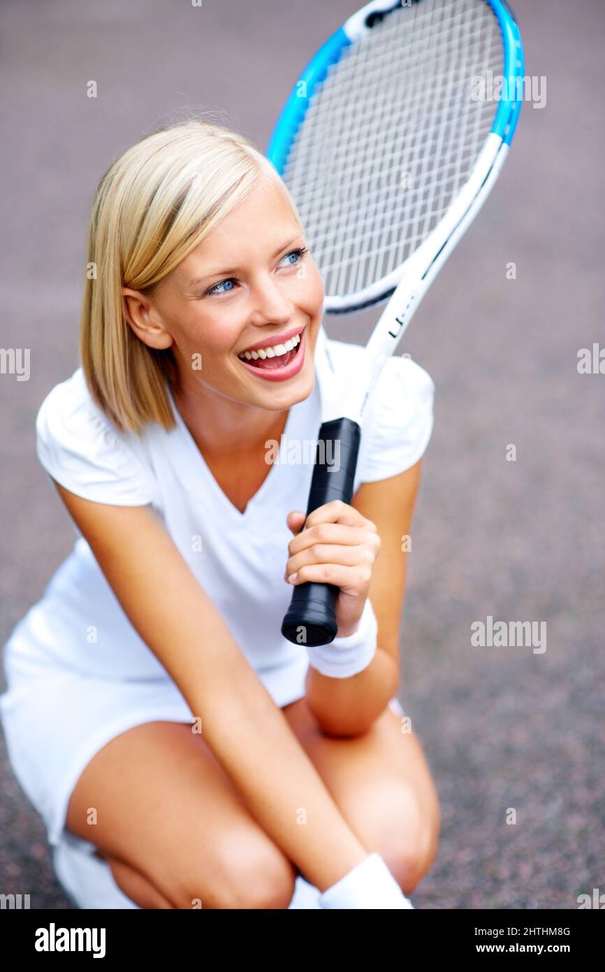 Rire de la joie du succès. Un jeune joueur de tennis qui s'agenouille et rêve de gagner son match. Banque D'Images