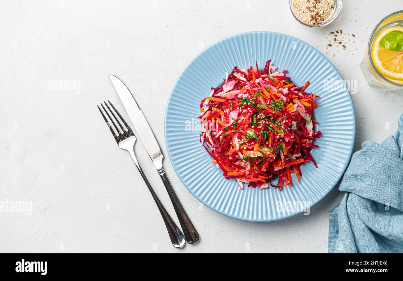 Salade végétalienne saine de printemps avec chou, betteraves et carottes assaisonnées d'aneth et de sésame sur fond gris. Le concept d'un régime alcalin. Banque D'Images