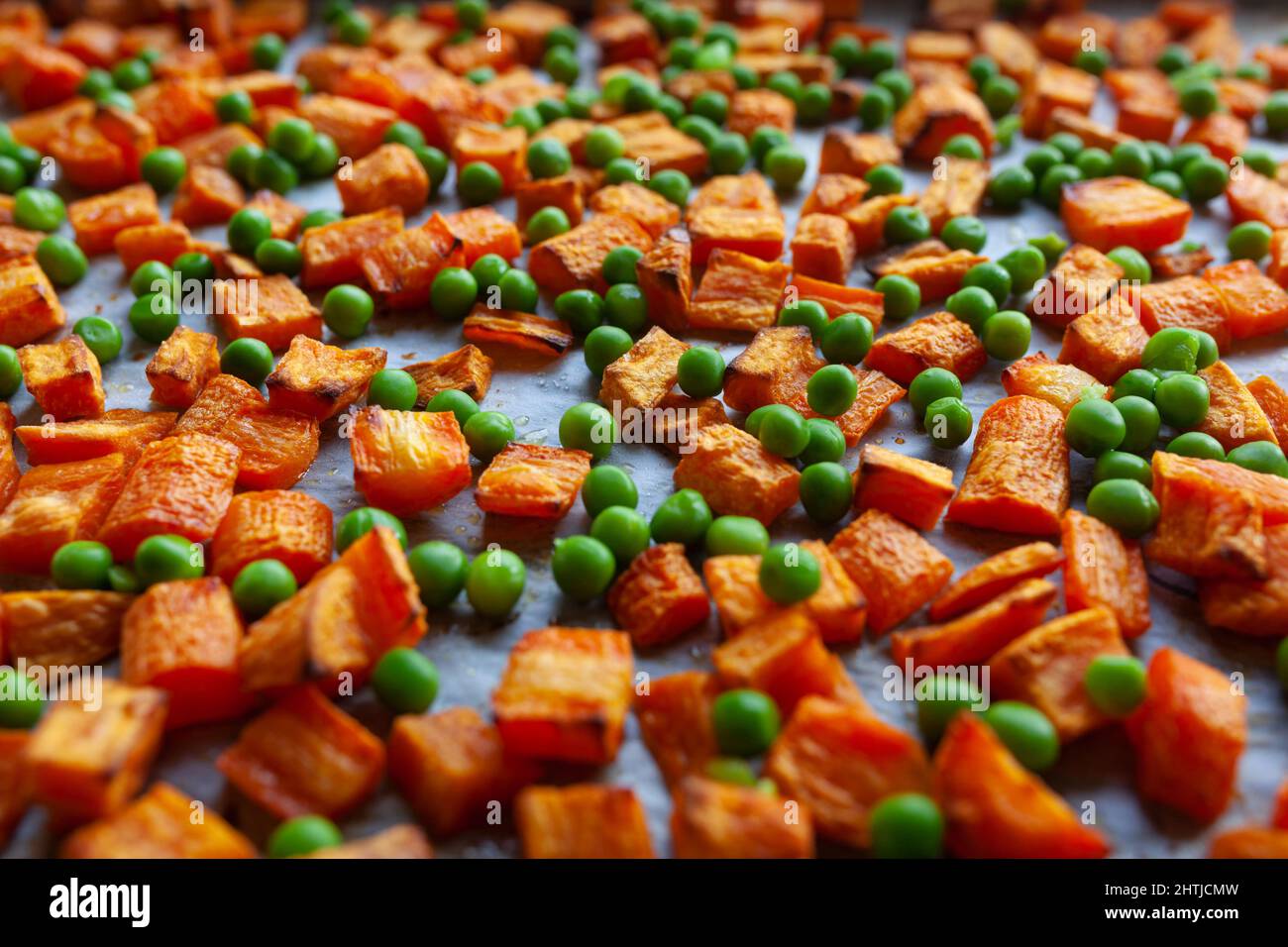 Carottes grillées au four, patates douces et petits pois verts sur papier parchemin, coupés en cubes Banque D'Images