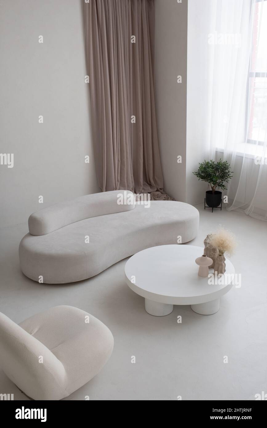 Cet appartement contemporain fait partie d''un salon spacieux et élégant comprenant un mobilier blanc et des rideaux aux couleurs pastel Banque D'Images