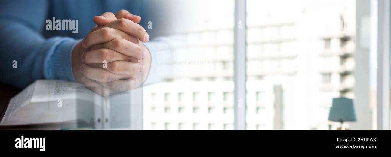 Mi-section d'une personne priant sur une sainte bible contre les fenêtres avec l'espace de copie Banque D'Images