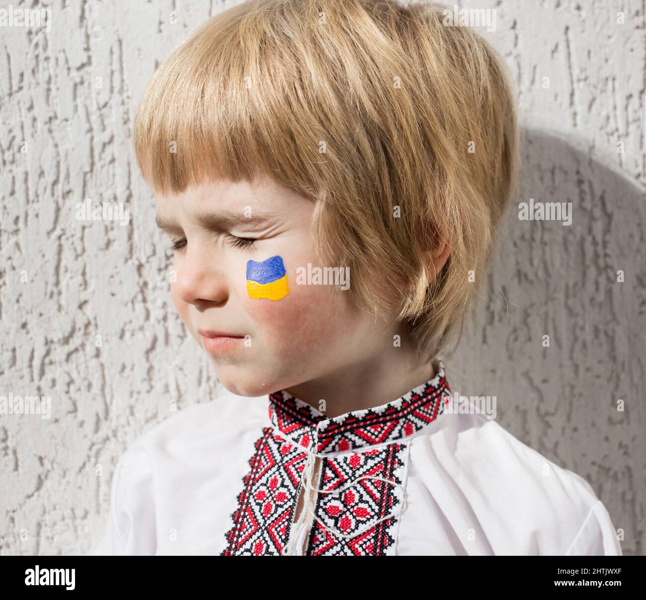 Le visage du garçon, le drapeau ukrainien est peint sur la joue avec des couleurs jaune et bleu. Invasion russe de l'Ukraine, pas de guerre. Demandez l'aide du monde c Banque D'Images