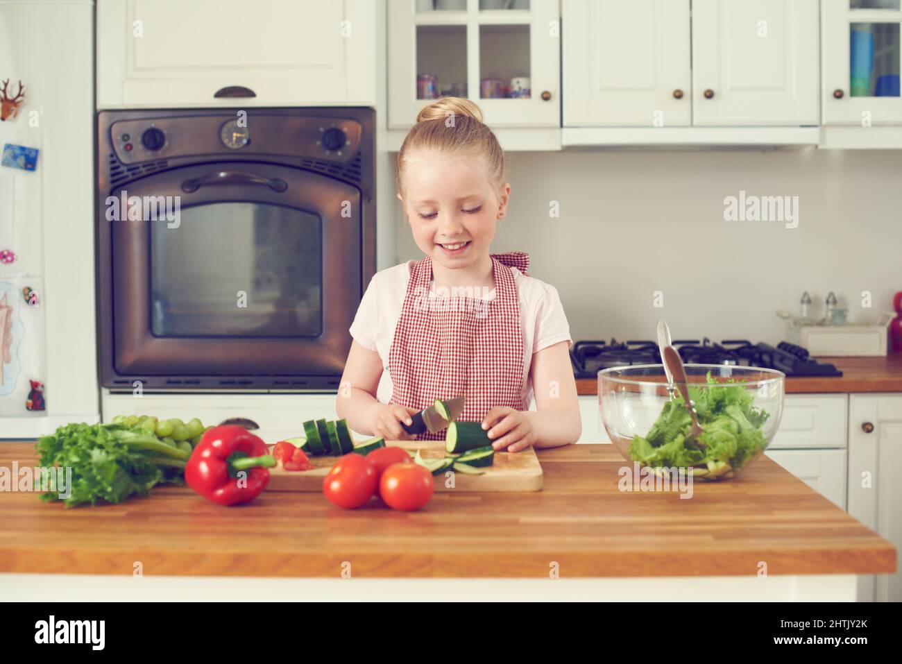 Elle aime faire des salades. Petite fille mignonne faisant une salade à la maison dans la cuisine. Banque D'Images