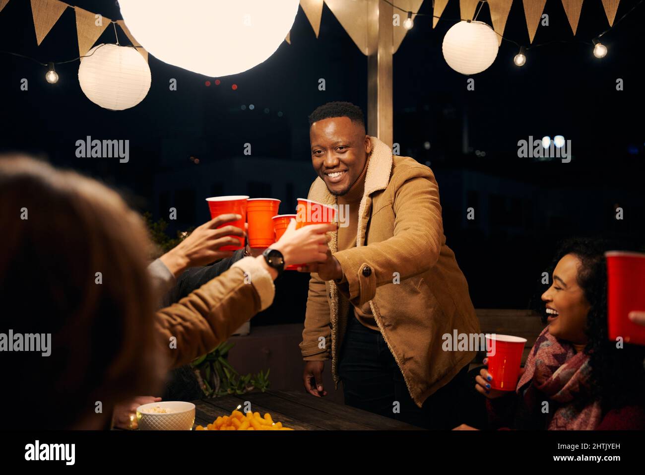 Homme noir debout, acclamations avec un groupe d'amis divers célébrant lors d'une fête en plein air Banque D'Images