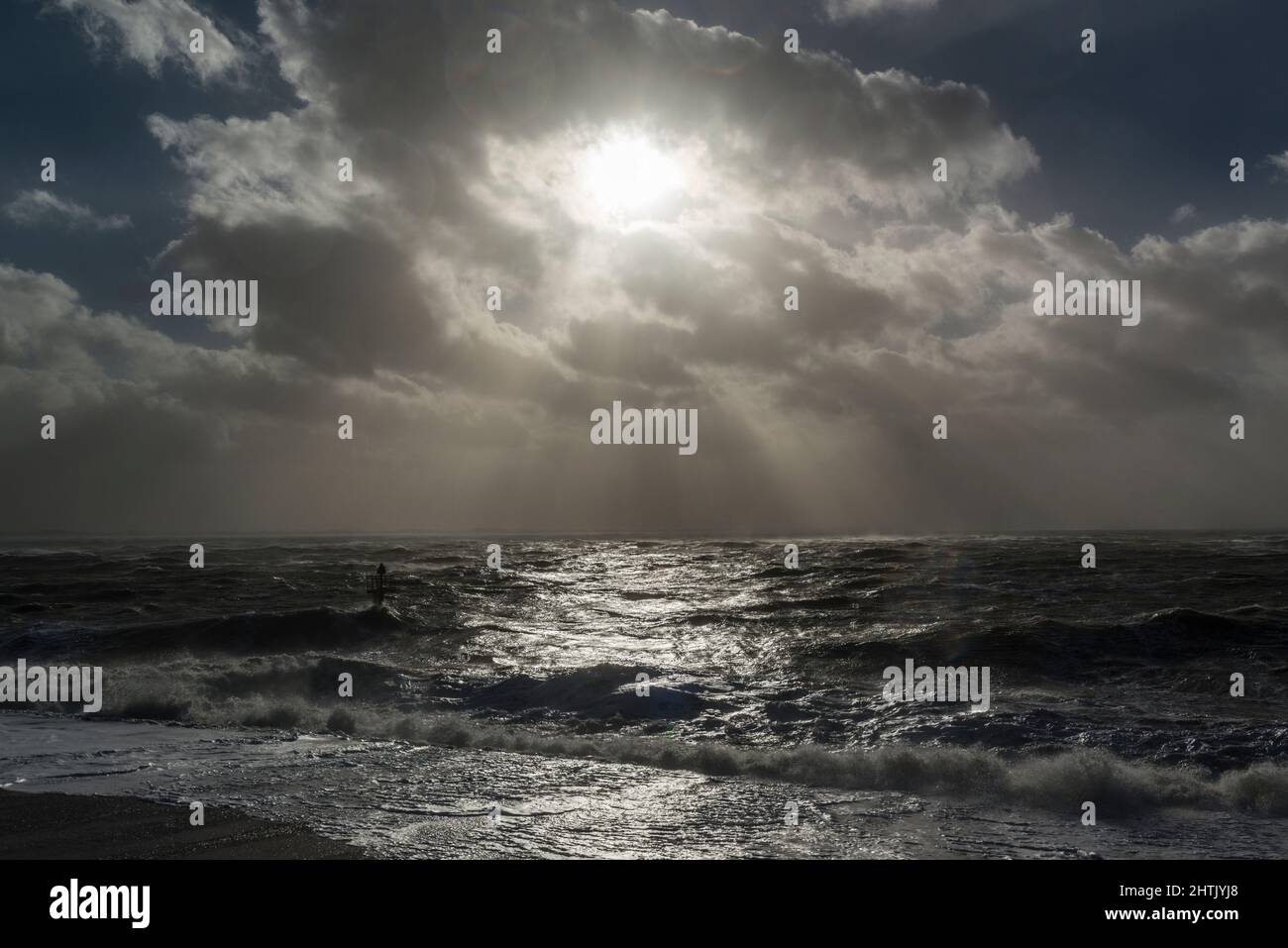 Les rayons du soleil de derrière les nuages brillent sur les vagues de turbulence pendant la tempête intense Eunice sur la côte à Vlissingen, pays-Bas Banque D'Images