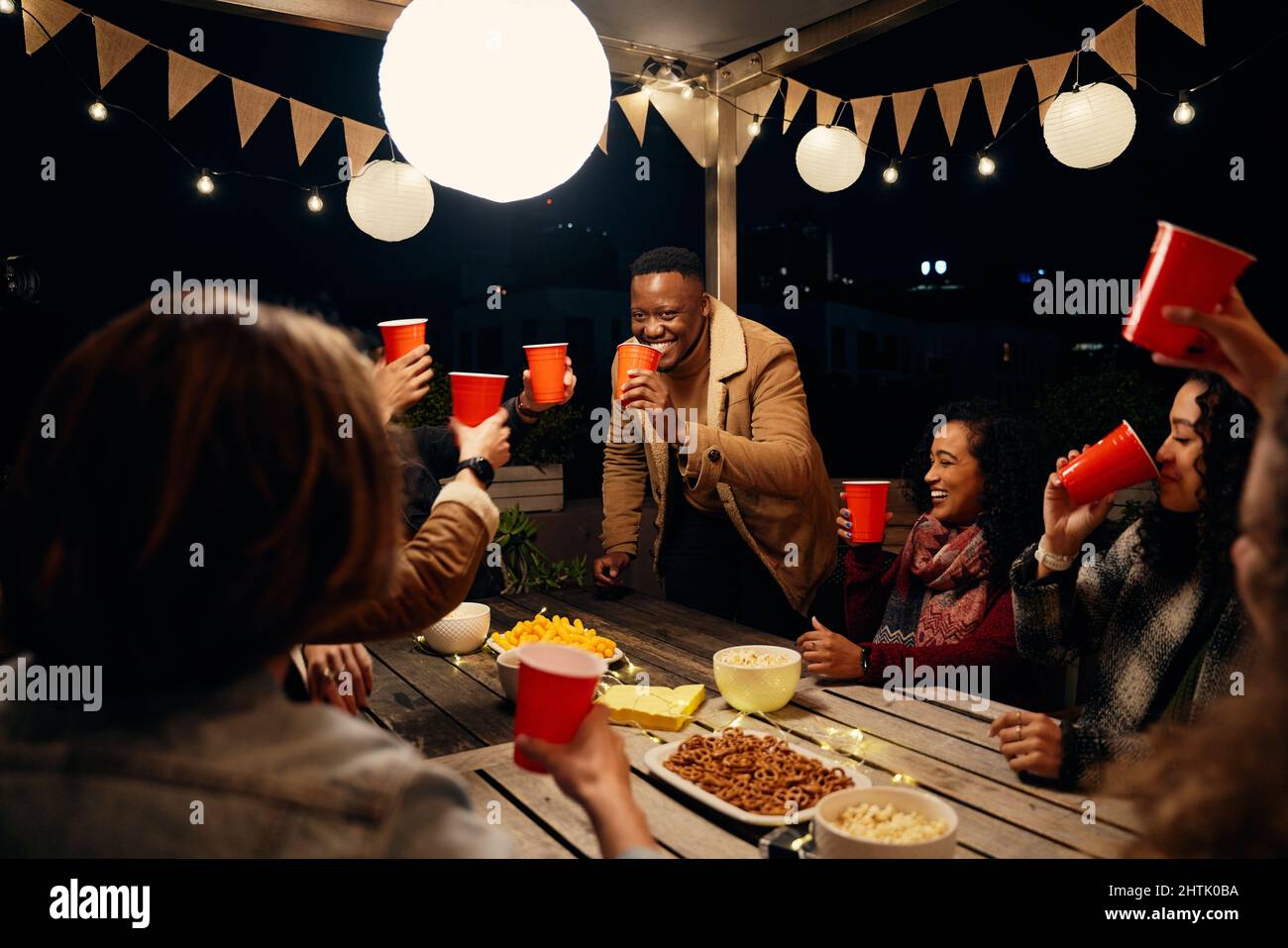 Homme noir debout, faisant des toasts à la fête sur le toit avec un groupe de divers amis à une fête en plein air Banque D'Images