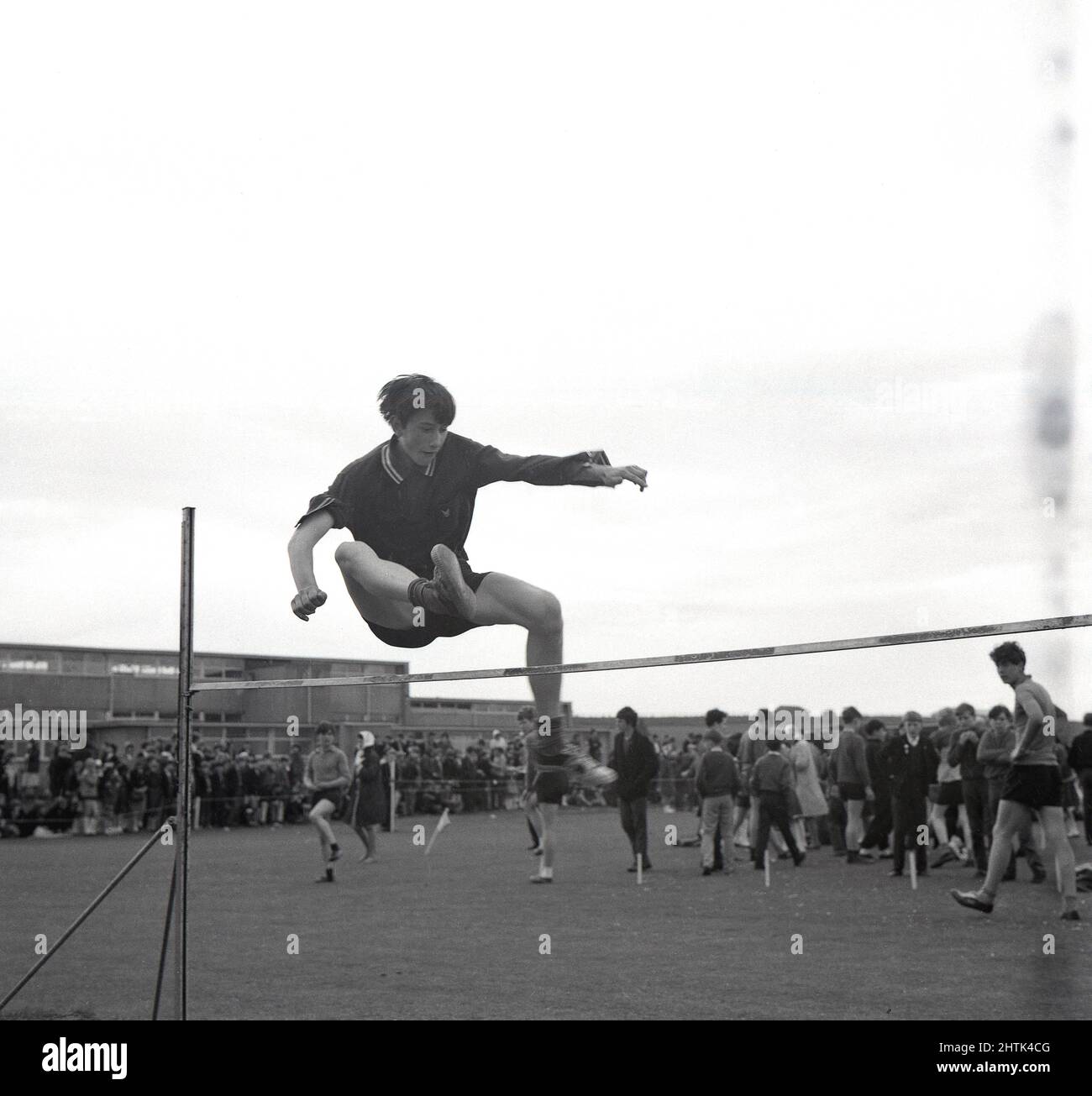 1960s, historique, sports scolaires, un adolescent faisant le saut à la hausse, en utilisant sa propre technique, Écosse, Royaume-Uni. Banque D'Images