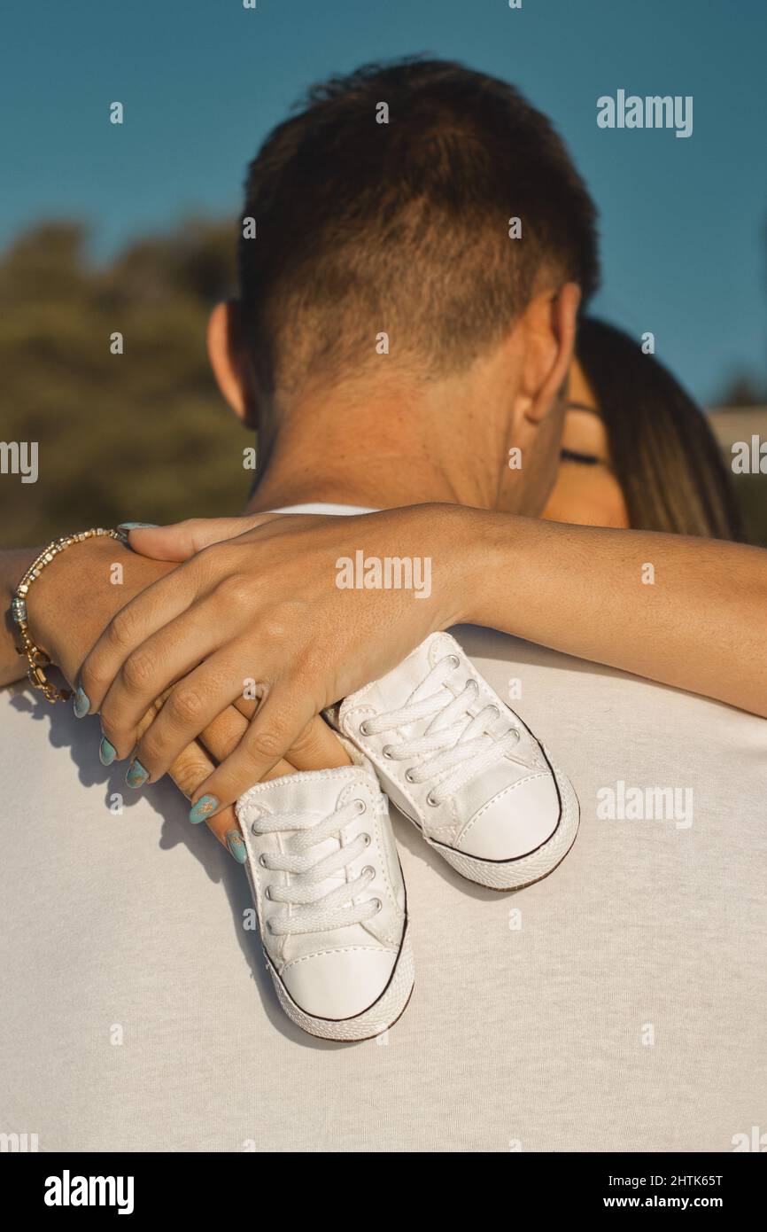 Annonce de grossesse, les femmes enceintes embrassent son mari après l'avoir révélé qu'elle est enceinte avec des chaussures de bébé. Banque D'Images