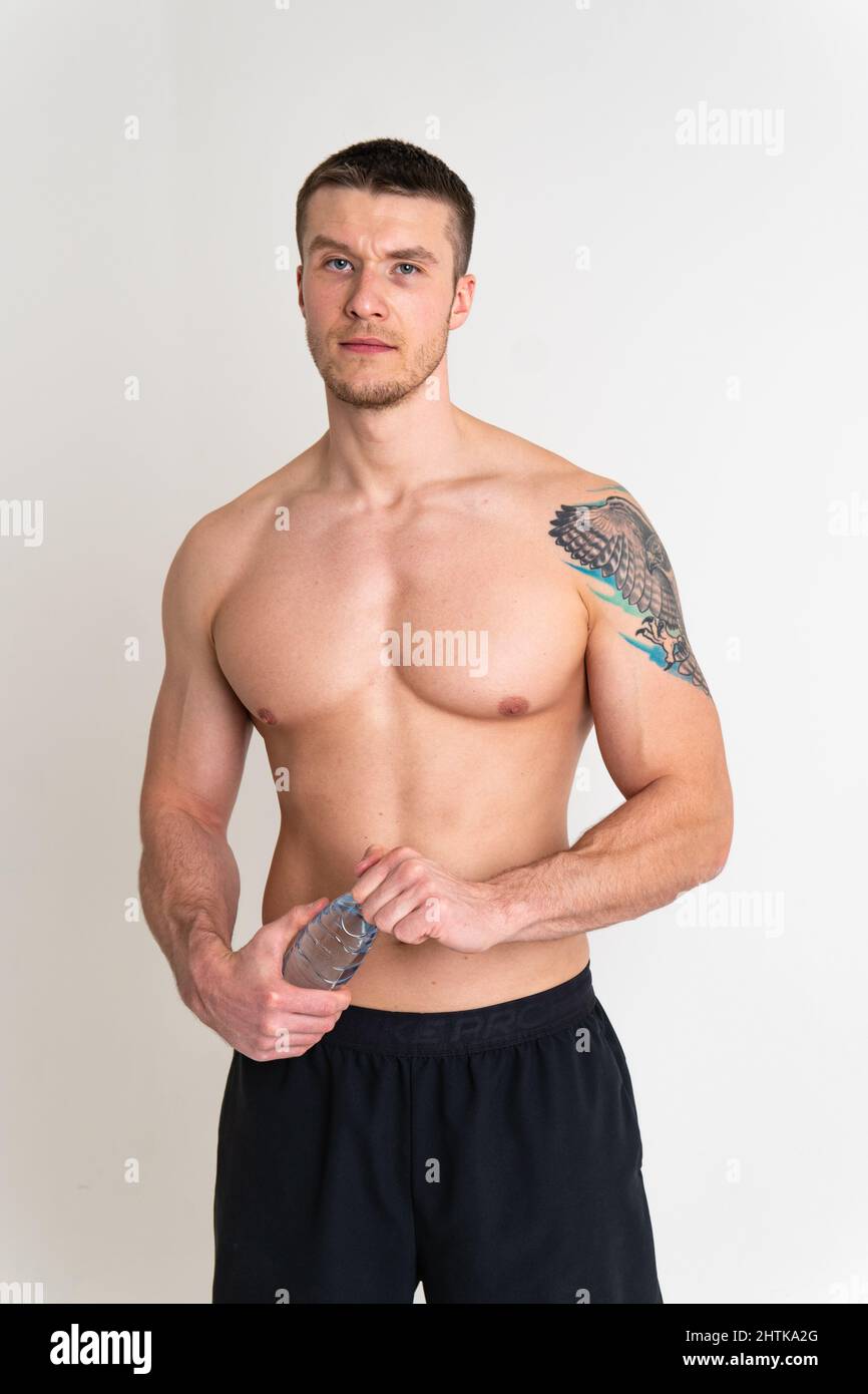 La forme physique masculine de l'eau potable est pompée avec une serviette sur un fond blanc corps isolé, l'entraînement des muscles sains d'adulte masculin athlétique. Protéine de serviette Banque D'Images