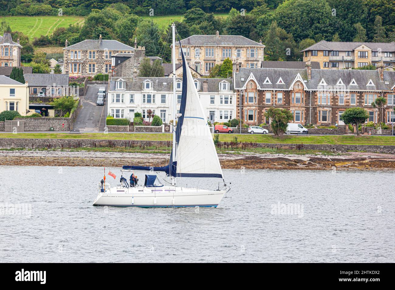 Un yacht passant devant la ville de Rothesay dans la baie de Rothesay sur l'île de Bute, Argyll & Bute, Écosse, Royaume-Uni Banque D'Images