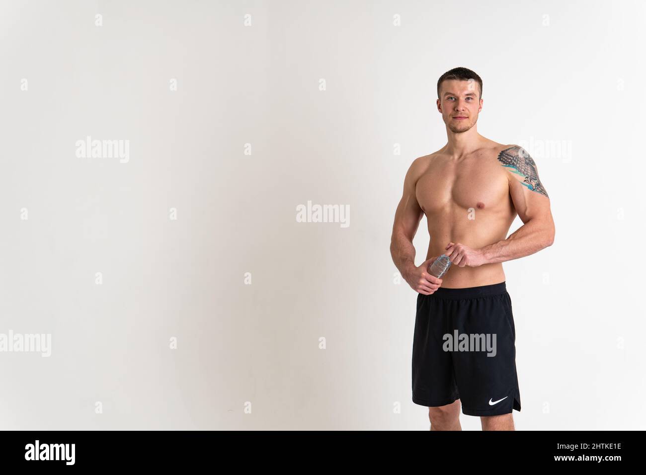 La forme physique à l'eau potable est pompée avec une serviette sur un fond blanc coupe isolée style de vie d'athlète, sport sportswear adulte arrière-plan athlétique Banque D'Images