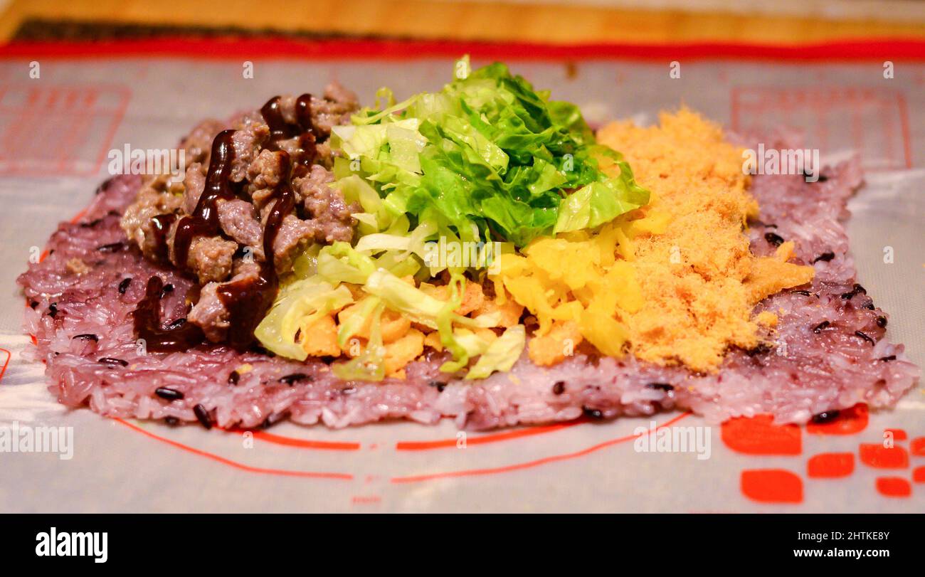 Riz sushi recouvert de délicieux légumes et garnitures de viande placées sur un tapis. Banque D'Images
