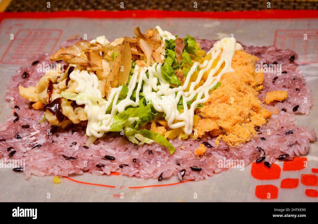 Riz sushi recouvert de délicieux légumes et garnitures de viande placées sur un tapis. Banque D'Images
