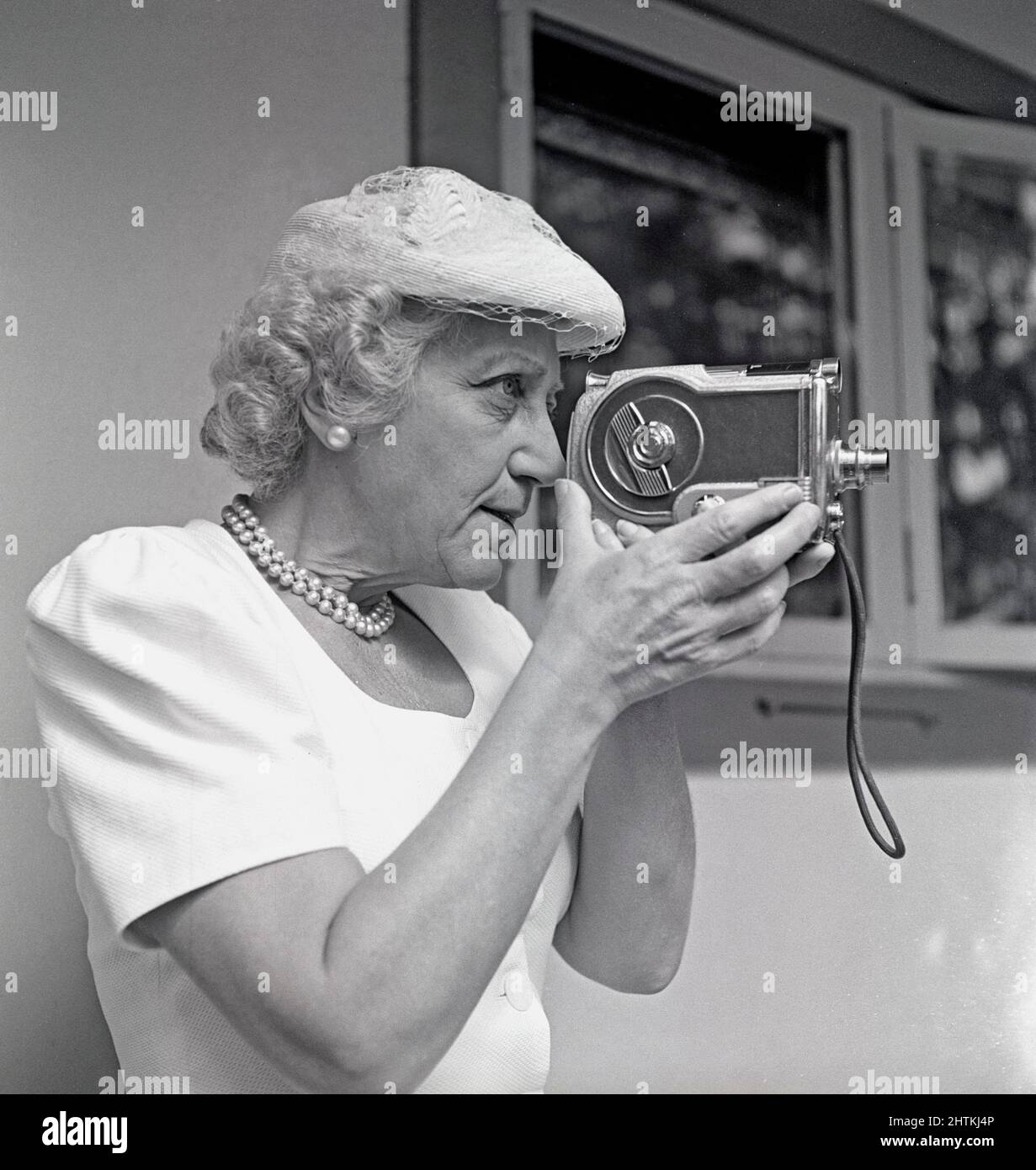 Le tournage amateur en 1940s. Une femme âgée utilise un appareil-photo, le tient et le vise à quelque chose. Un équipement amateur pour filmer des films à regarder à la maison. Suède 1948 Kristoffersson réf. AL31-3 Banque D'Images