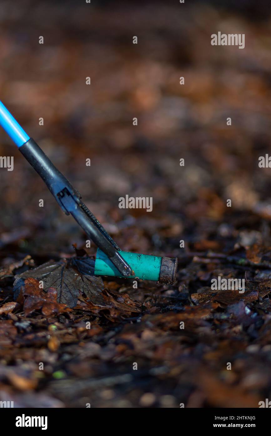 Près d'une cartouche de fusil de chasse mise au rebut, mais d'un picker de litière. Collecte de litière, déchets, concept environnemental Banque D'Images