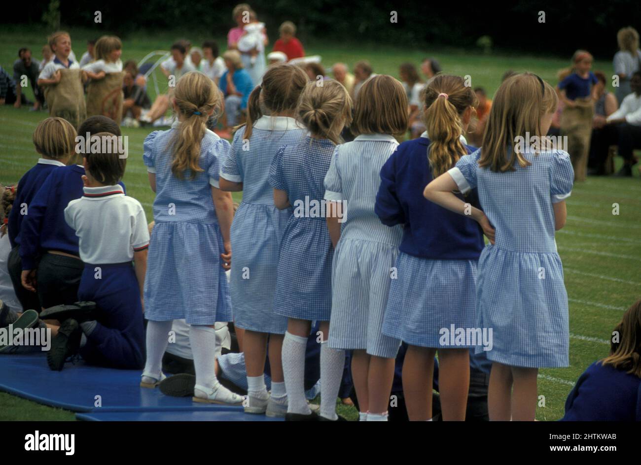 rangée de filles d'école primaire en uniforme regardant des événements sportifs de jour Banque D'Images