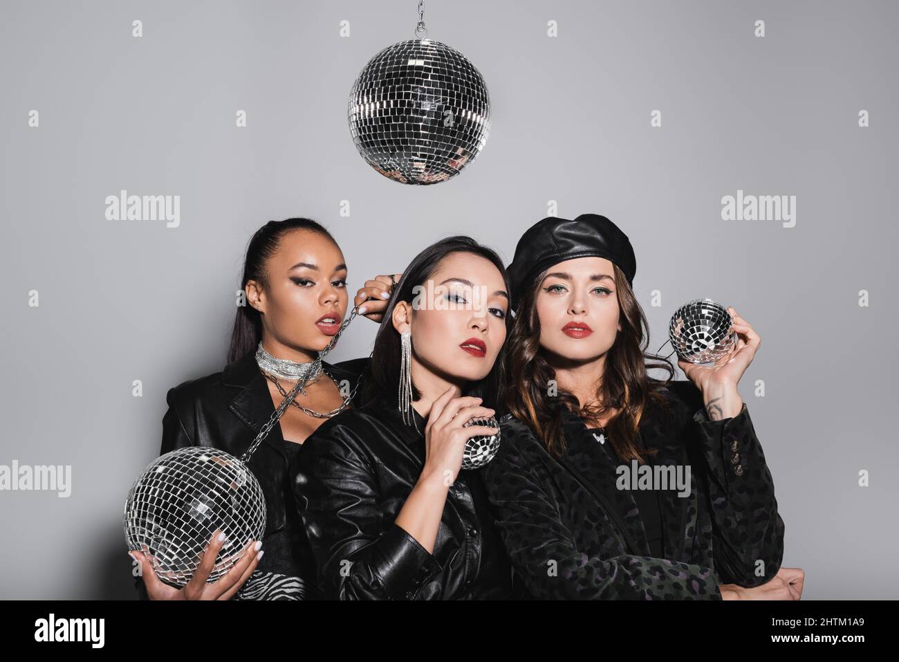 jeune afro-américaine posant près de modèles interraciaux tenant des boules disco sur le gris Banque D'Images