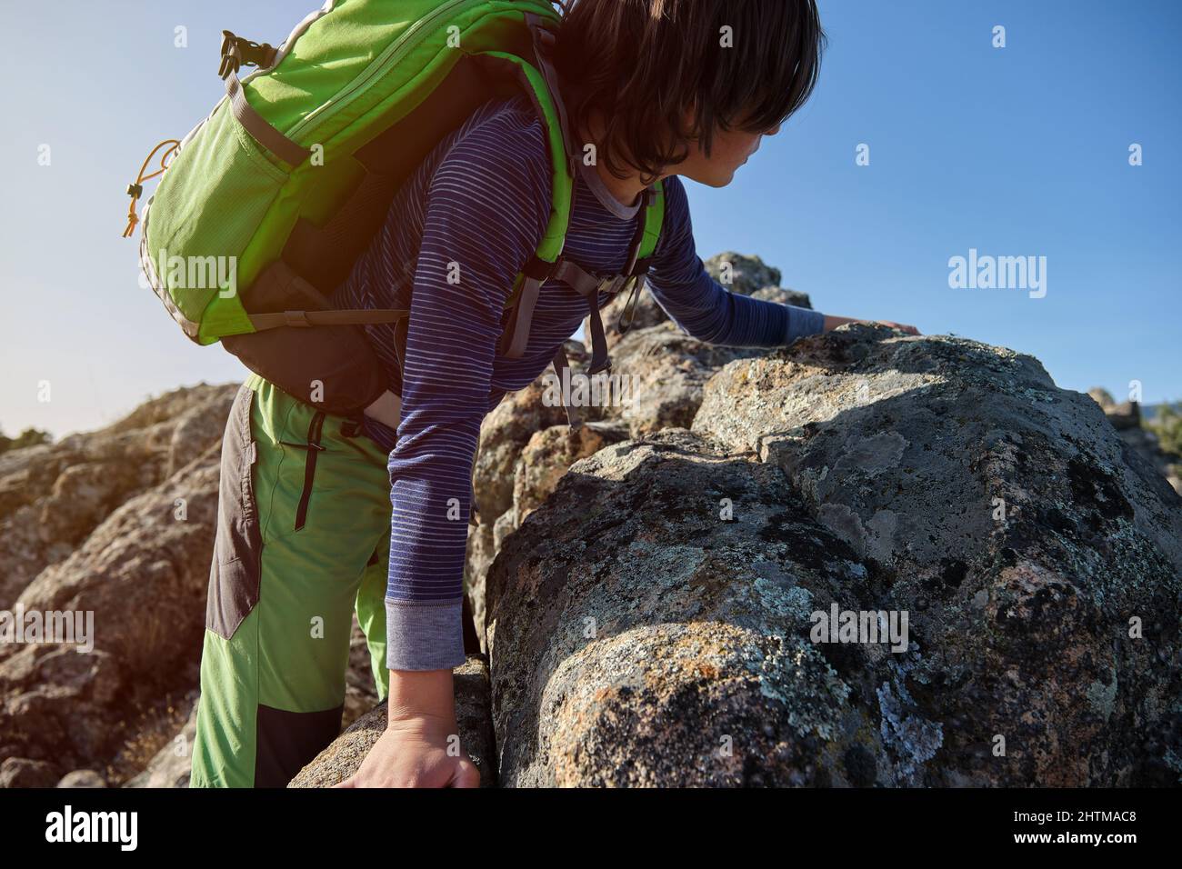 Adolescent avec sac à dos grimpant des rochers dans la nature Banque D'Images