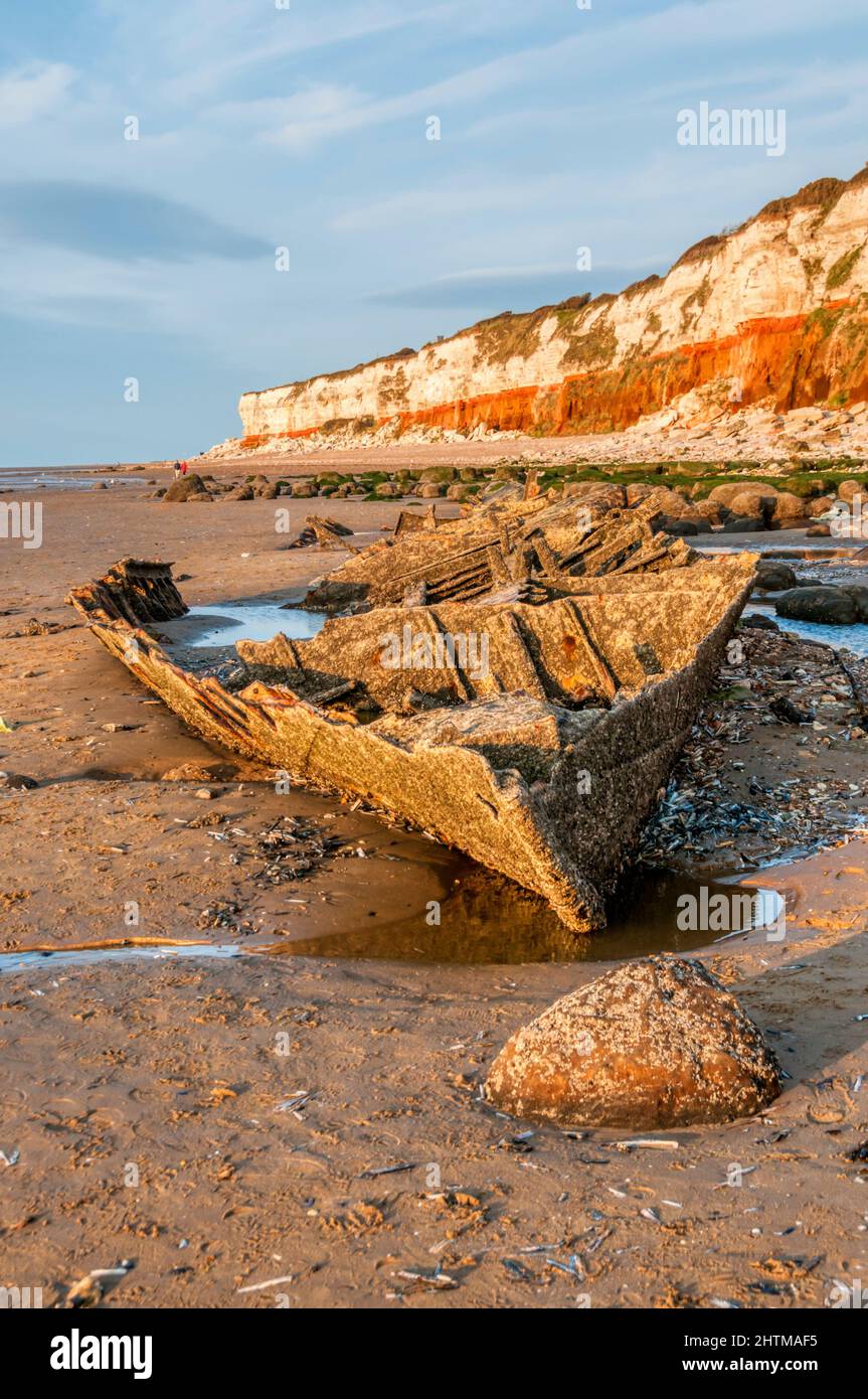 L'épave du Sheraton du chalutier à vapeur sous les falaises rayées rouges et blanches de Hunstanton à marée basse. Banque D'Images