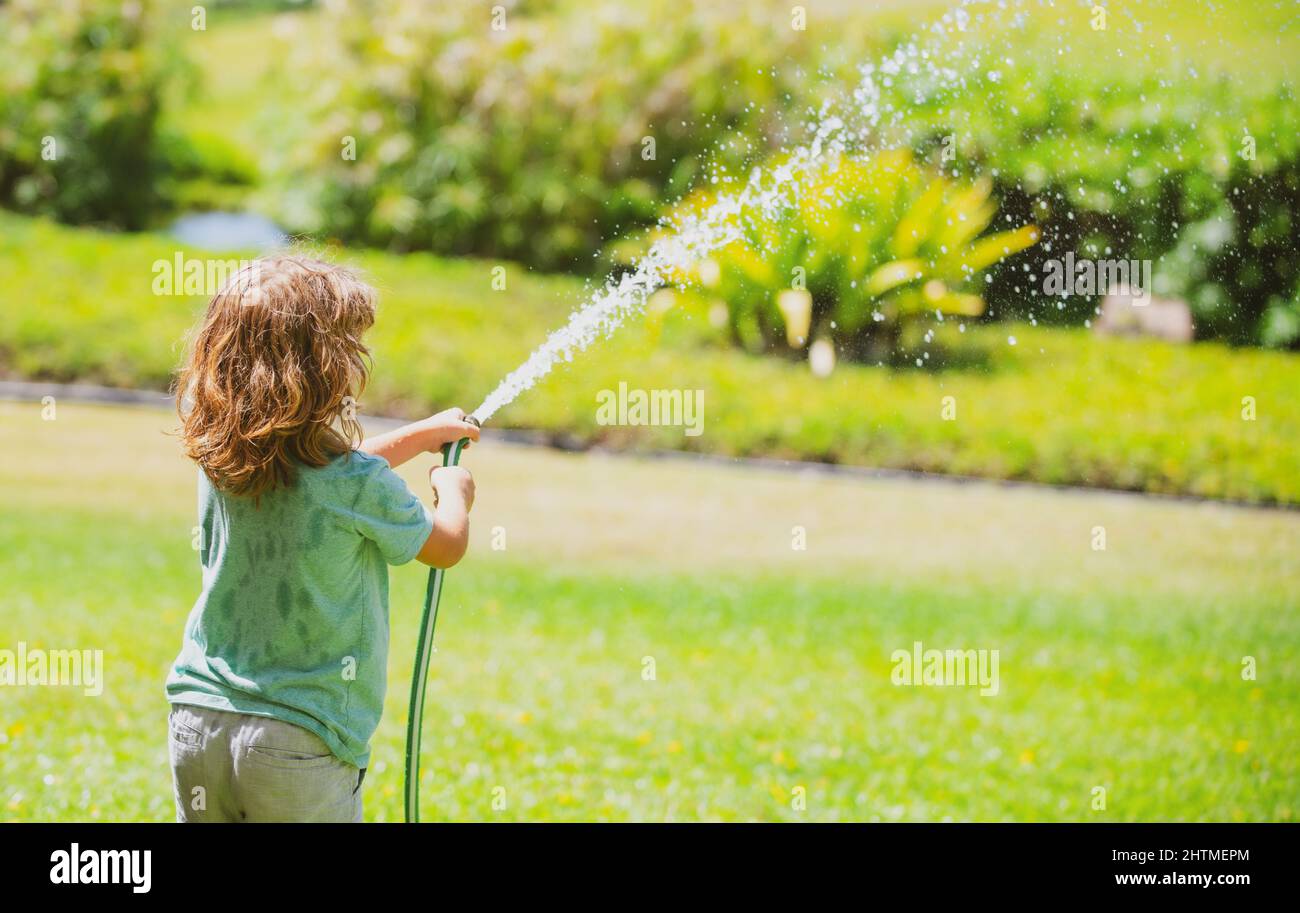 Les enfants jouent avec le tuyau d'arrosage dans la cour. Jeux d'été pour  enfants en plein air. Petit garçon jouant avec le tuyau d'eau dans  l'arrière-cour. Jeu de fête pour les enfants