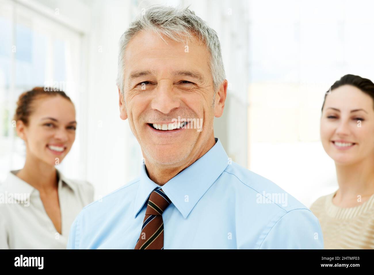 Homme d'affaires souriant avec des collègues à l'arrière. Portrait d'un homme d'affaires souriant avec des collègues en arrière-plan. Banque D'Images