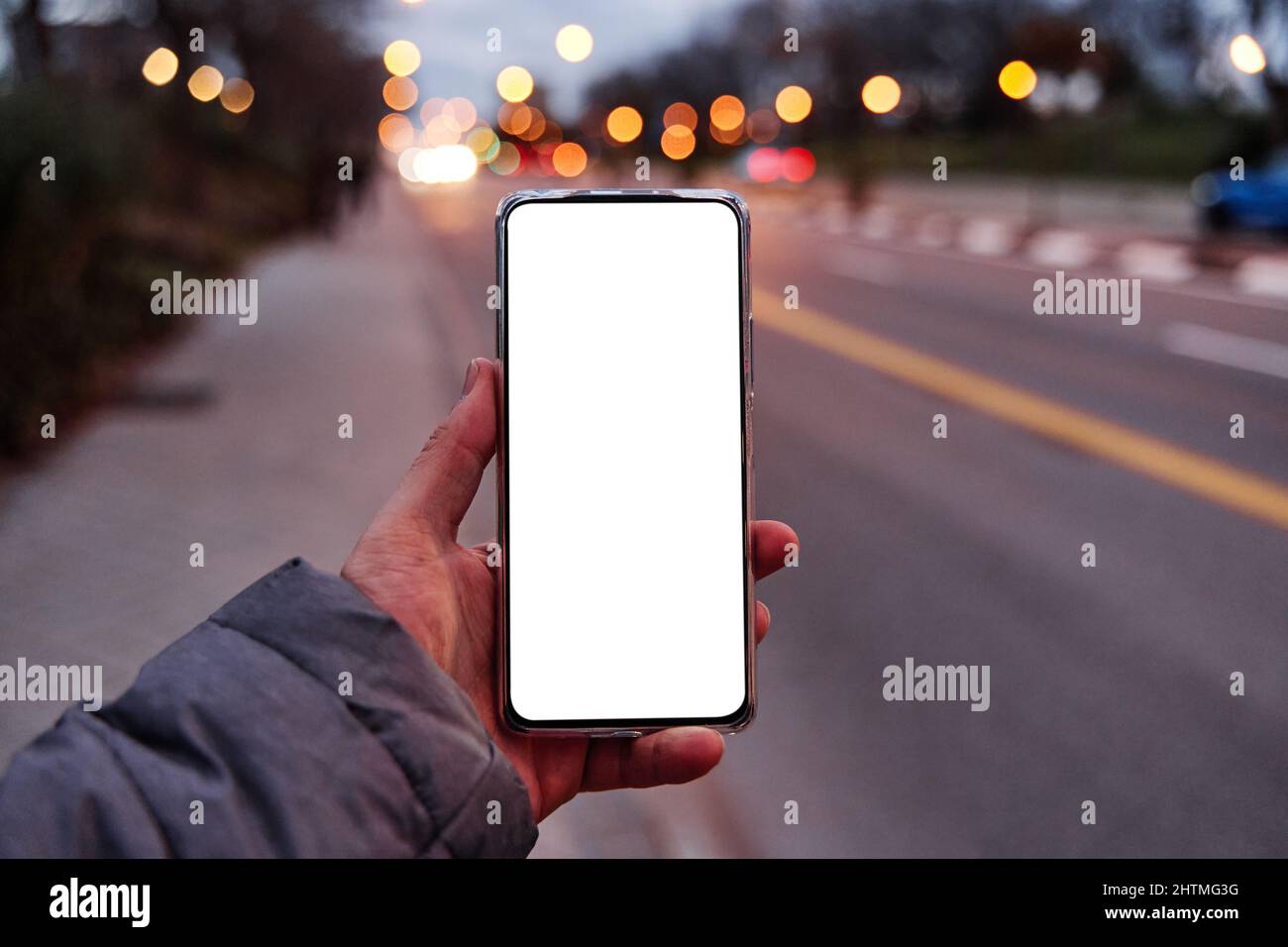 smartphone portable avec écran vierge avec espace de copie pour votre design ou logo, maquette de téléphone mobile, rue de ville du soir sur l'arrière-plan, boke Banque D'Images