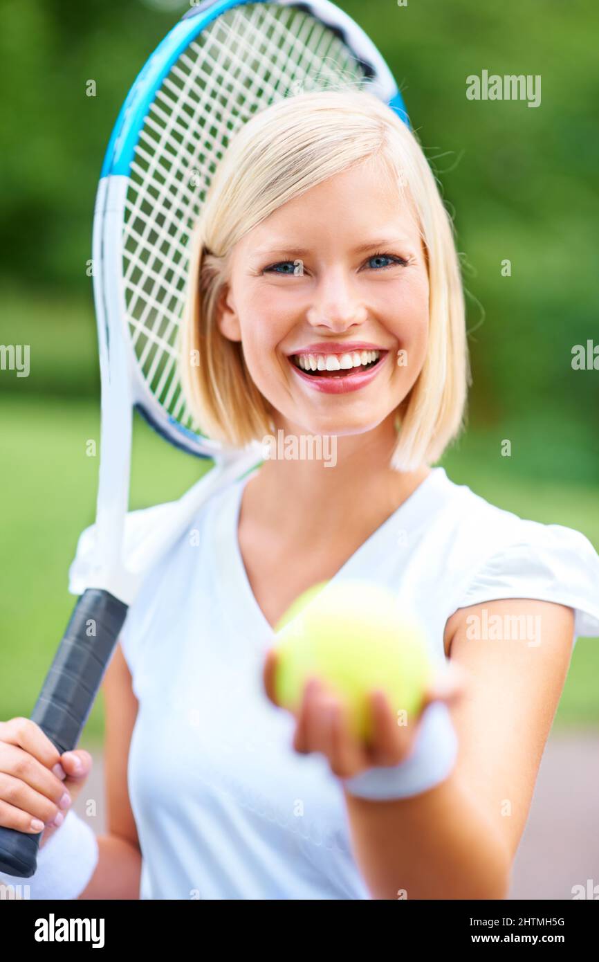 Êtes-vous à la hauteur ? Portrait d'une jeune joueuse de tennis tenant sa raquette et vous offrant le ballon. Banque D'Images