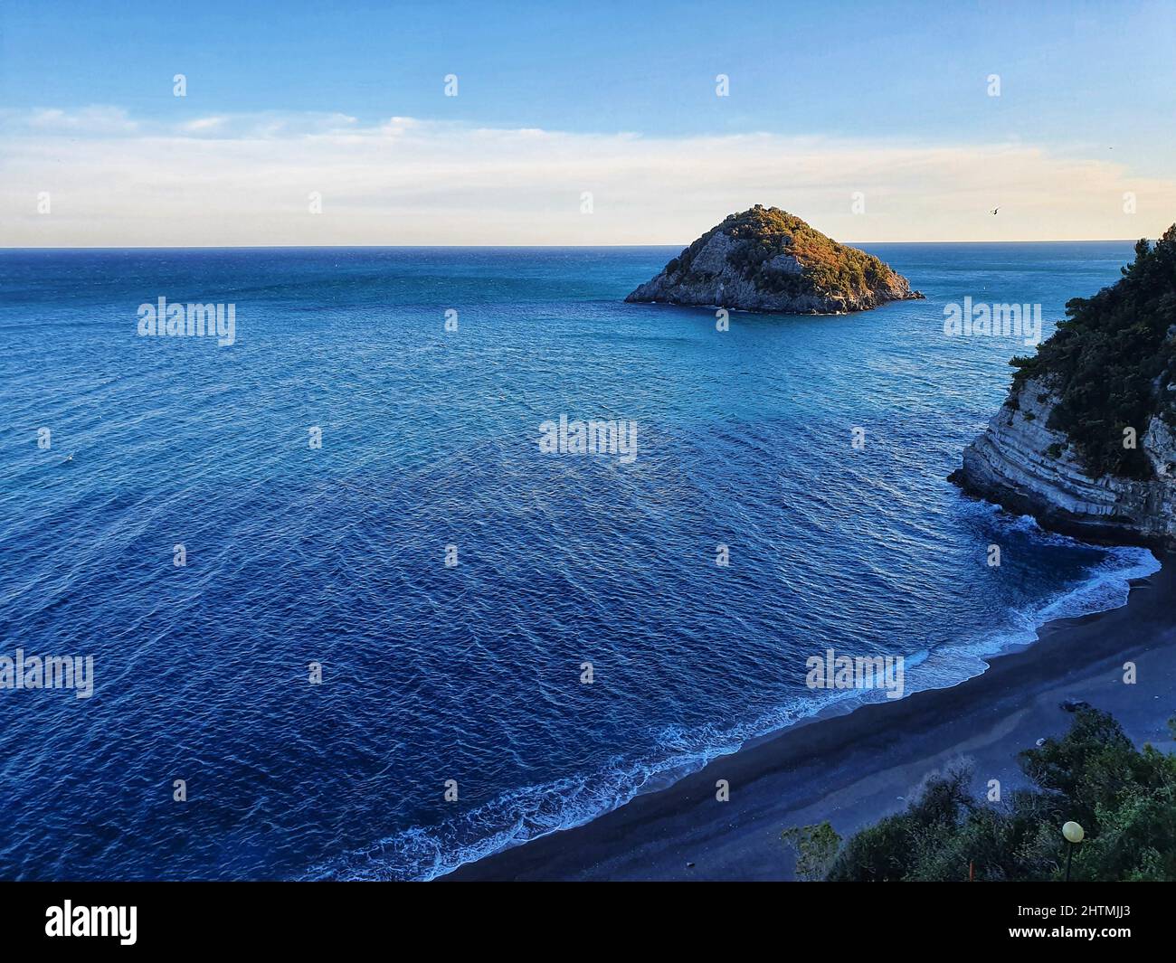 Vue sur un plan d'eau et une pierre géante près d'un rivage avec des nuages légers en arrière-plan Banque D'Images