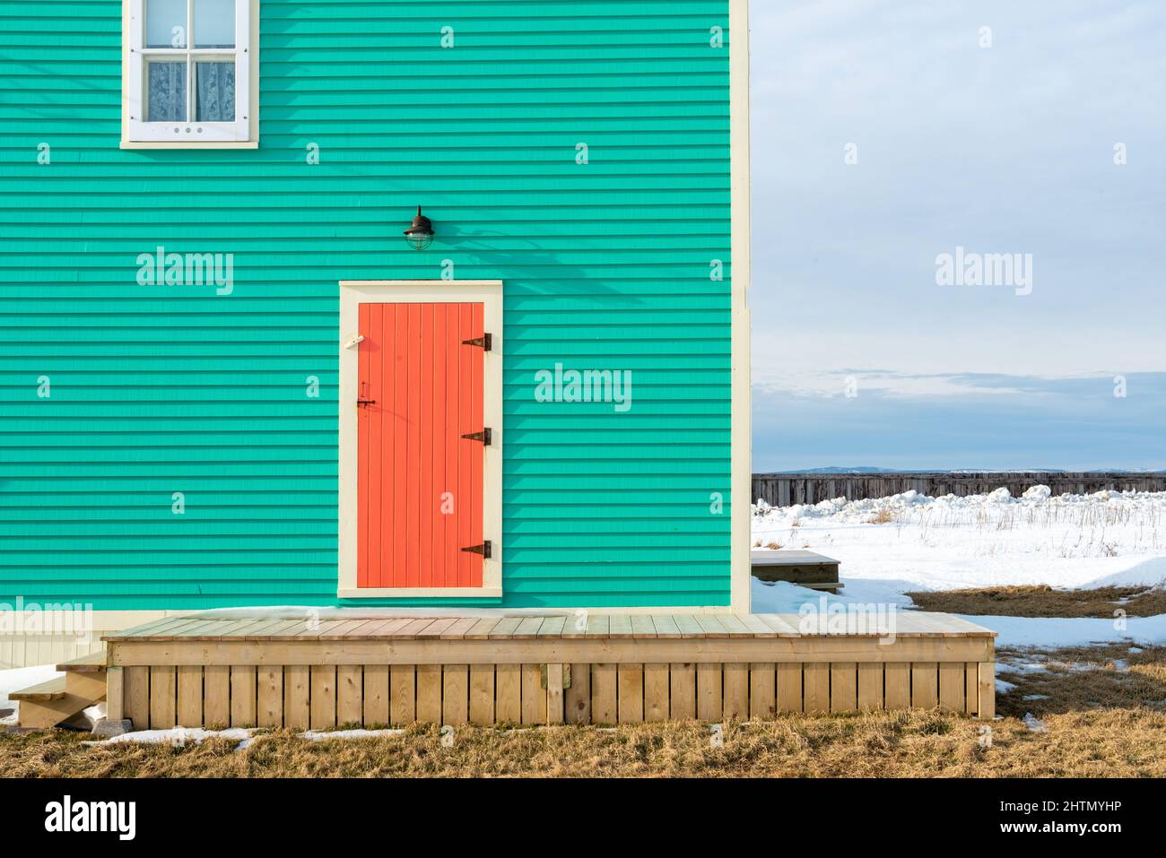 Une porte de volet en bois traditionnel avec garniture de couleur crème sur un mur de couleur vert sarcelle d'une maison avec une seule fenêtre suspendue. Banque D'Images