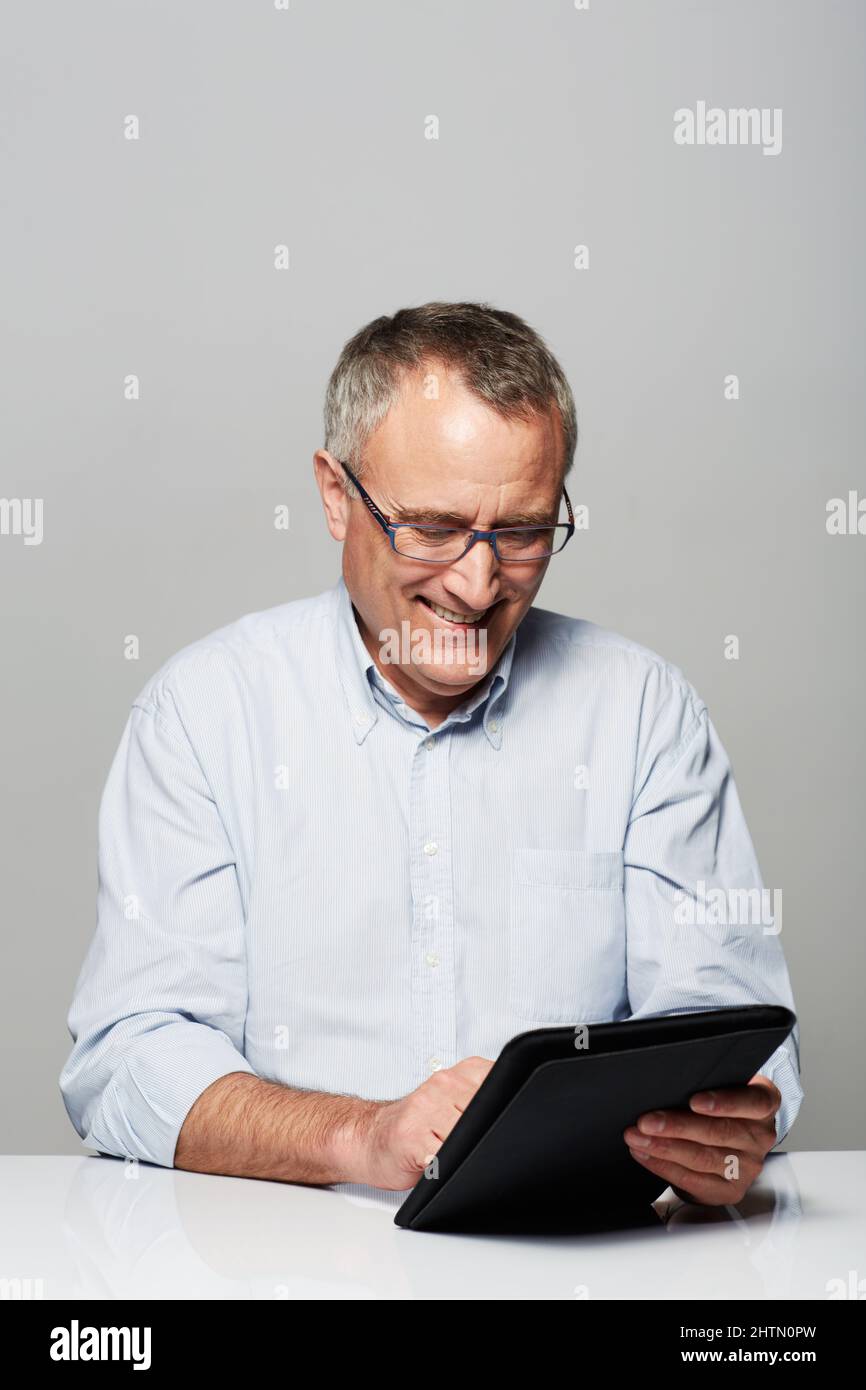 Vous n'êtes jamais trop vieux pour la technologie Photo en studio d'un homme mûr travaillant sur une tablette numérique. Banque D'Images