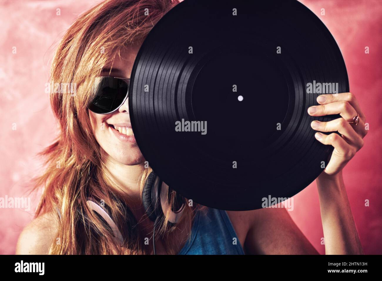 Les Golden Oldies sont toujours les meilleurs. Portrait amusant d'une jeune femme tenant un disque en vinyle jusqu'à son visage. Banque D'Images