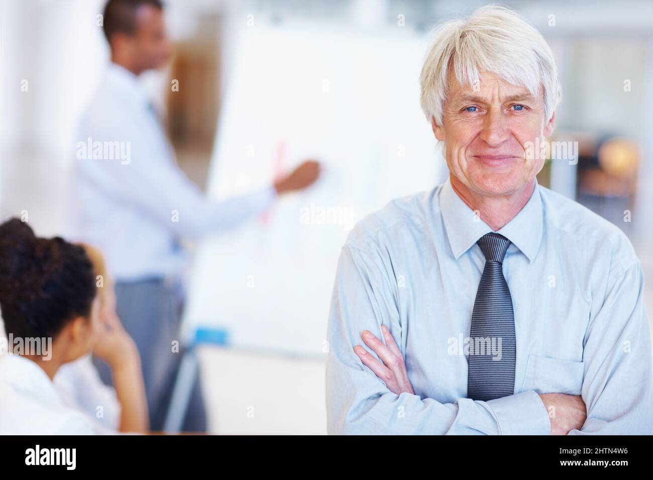 Homme d'affaires souriant avec des cadres. Portrait d'un homme d'affaires senior souriant avec des cadres en arrière-plan au bureau. Banque D'Images