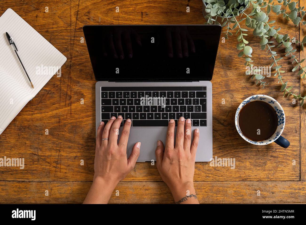 Vue en hauteur des mains d'une femme dactylographiant sur un ordinateur portable sur un vieux bureau en bois Banque D'Images Vue en hauteur des mains d'une femme dactylographiant sur un ordinateur portable sur un vieux bureau en bois Banque D'Images