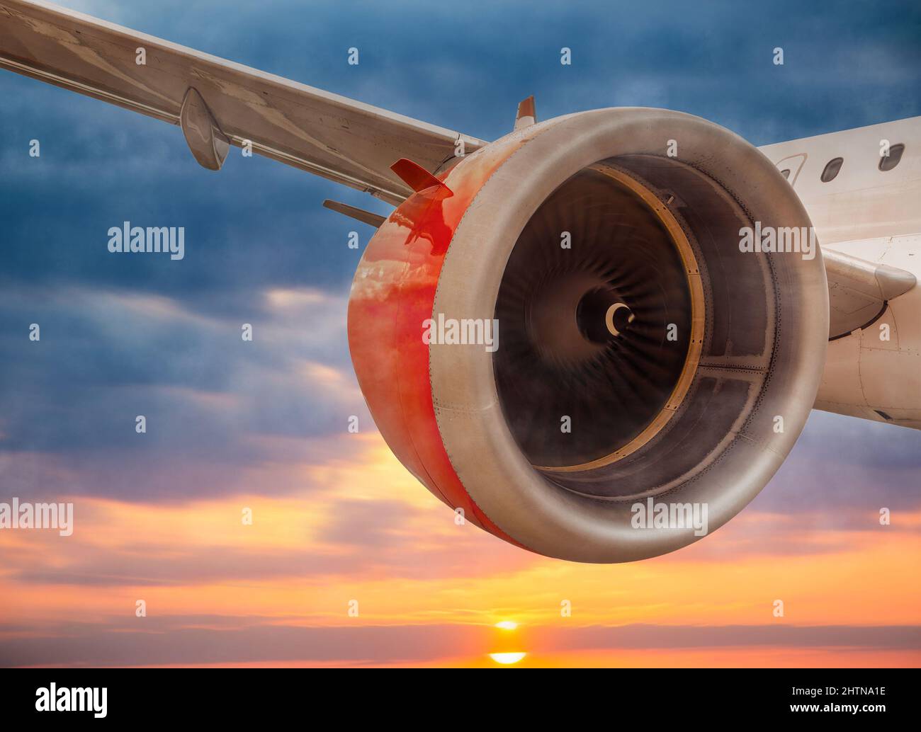 Gros plan de l'avion avec le moteur rouge tournant comme il vole au-dessus du ciel doré de coucher de soleil. Banque D'Images
