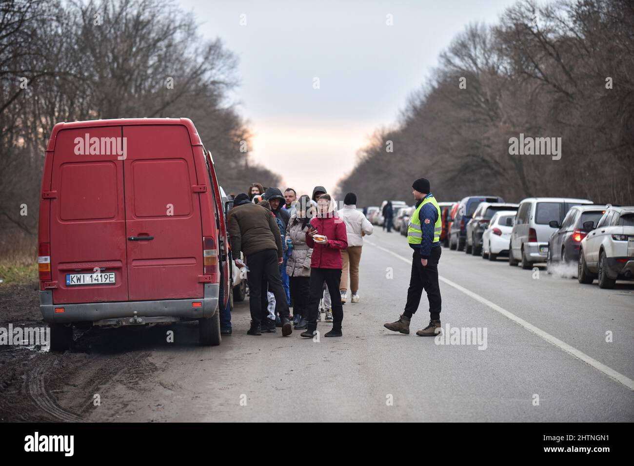 Des volontaires distribuent de la nourriture aux réfugiés qui attendent de traverser la frontière entre l'Ukraine et la Pologne au point de contrôle de Shehyni en raison d'une agression russe. Des milliers de personnes sont devenues des réfugiés forcés en raison de la guerre de la Russie en Ukraine. De nombreux réfugiés se dirigent vers la frontière ukrainienne-polonaise. Ainsi, la file d'attente de voitures jusqu'au point de contrôle de Shehyni s'étendait sur près de 20 kilomètres. Certaines personnes y attendent depuis cinq jours pour traverser la frontière. Quiconque veut traverser la frontière à pied est obligé de couvrir ces près de 20 kilomètres à pied. Banque D'Images