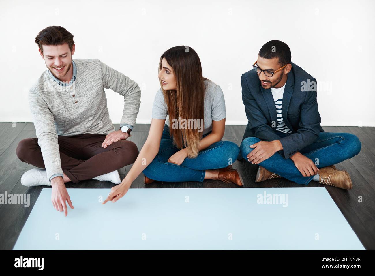 Chaque opinion compte. Photo studio d'un groupe de jeunes assis sur le sol et travaillant sur du papier vierge. Banque D'Images