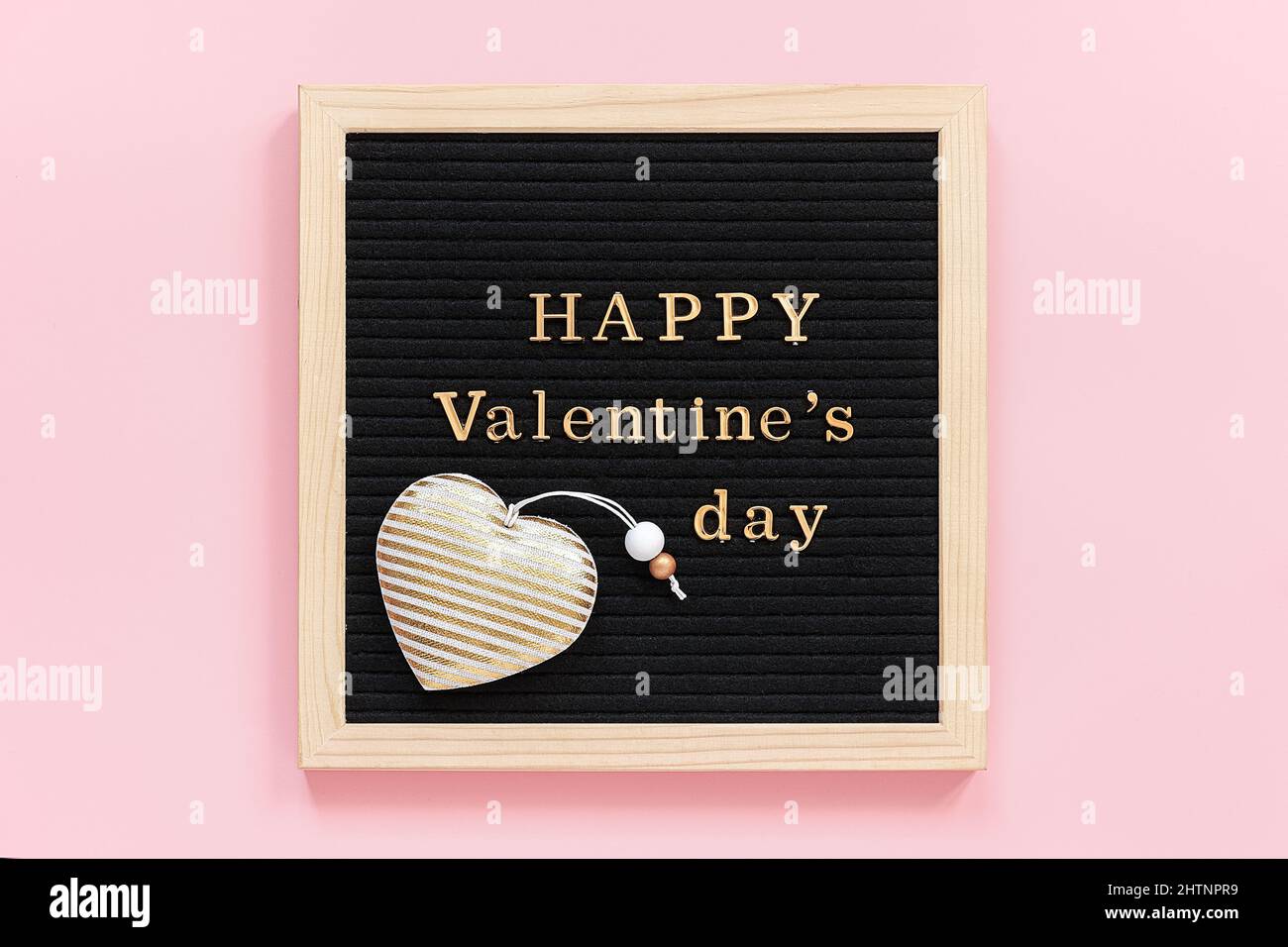Inscription dorée Happy Valentines Day et décoration coeur textile sur carton noir, composition centrale sur fond rose. Modèle pour Valen Banque D'Images