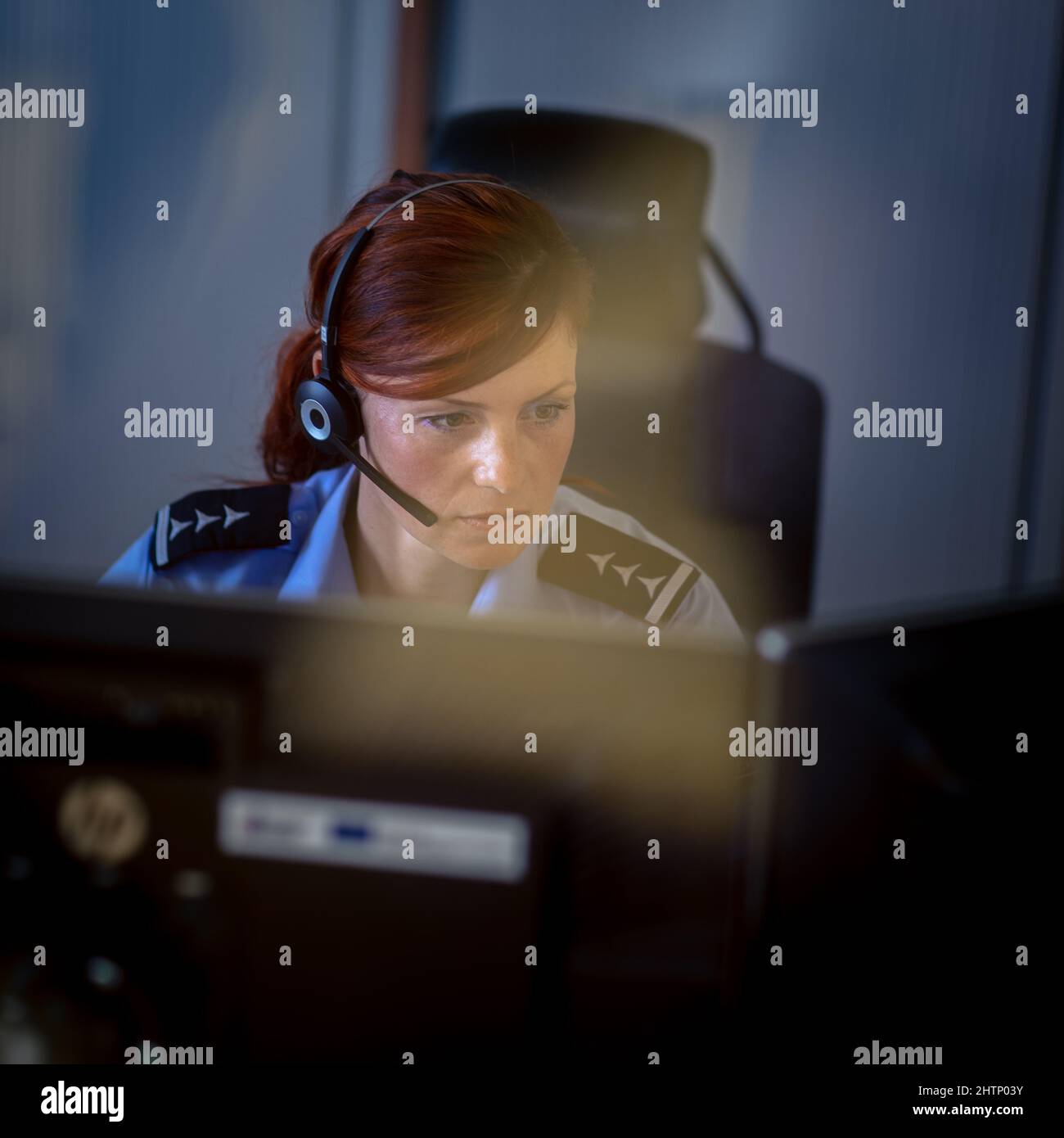 Une femme de police dans un centre d'appels, écoutant attentivement un appel d'urgence d'une personne en détresse Banque D'Images