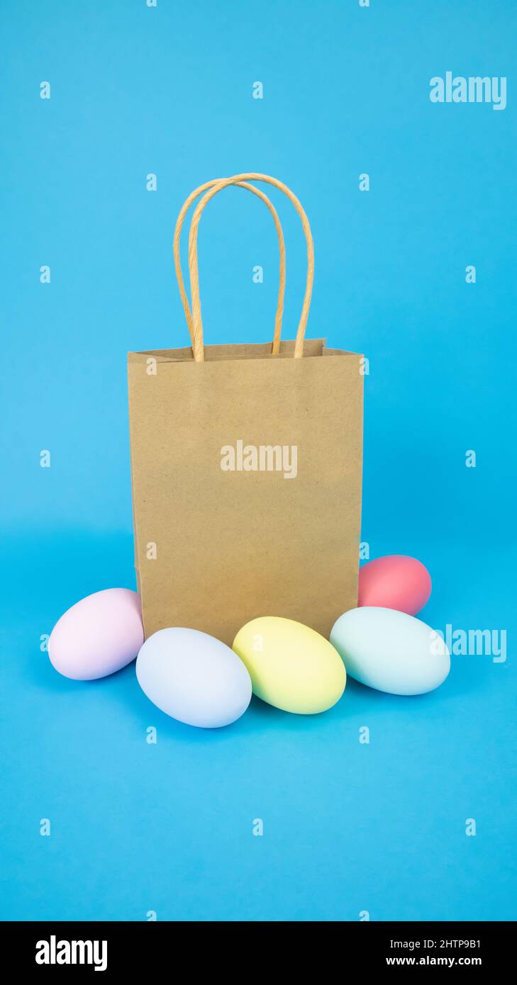 Pâques, sac en papier, cadeau et œufs sont simples, multicolores sur fond bleu Banque D'Images