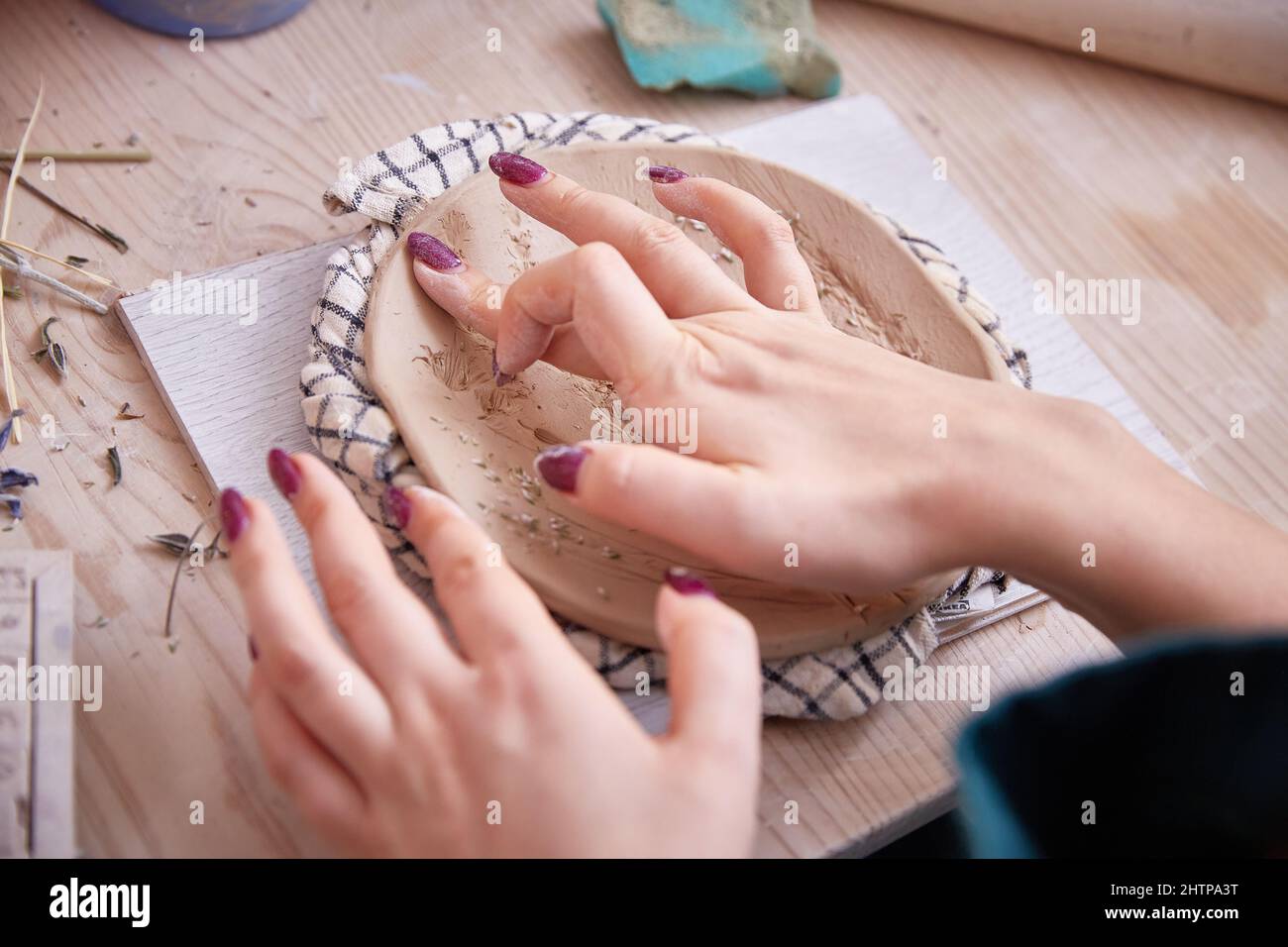 les mains des femmes d'un céramiste lissent une plaque ou un panneau figuré Banque D'Images
