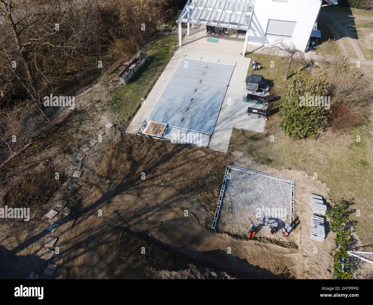 Un drone survolait une piscine couverte avec une bâche encore en construction dans un jardin Banque D'Images