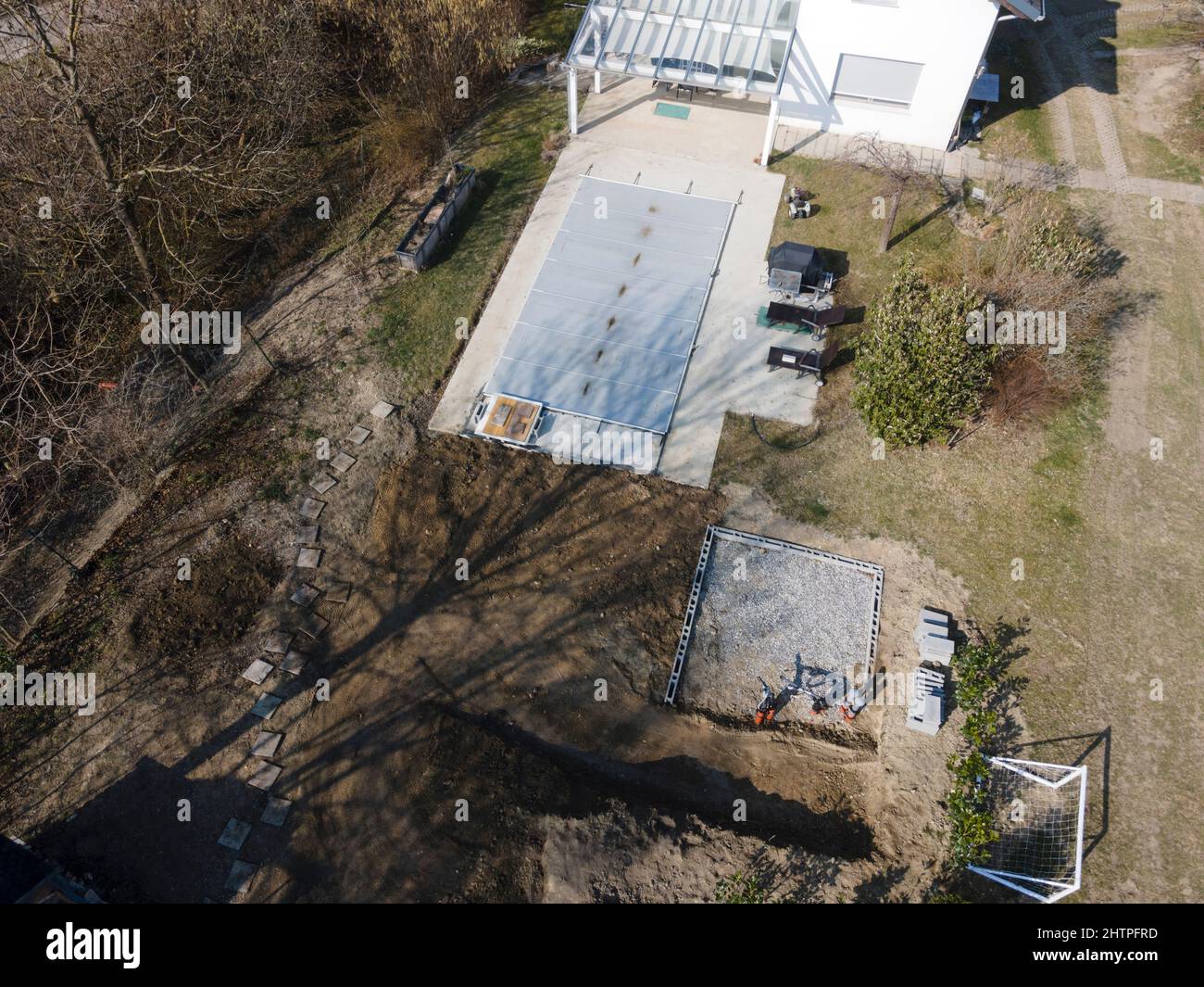 Un drone survolait une piscine couverte avec une bâche encore en construction dans un jardin Banque D'Images
